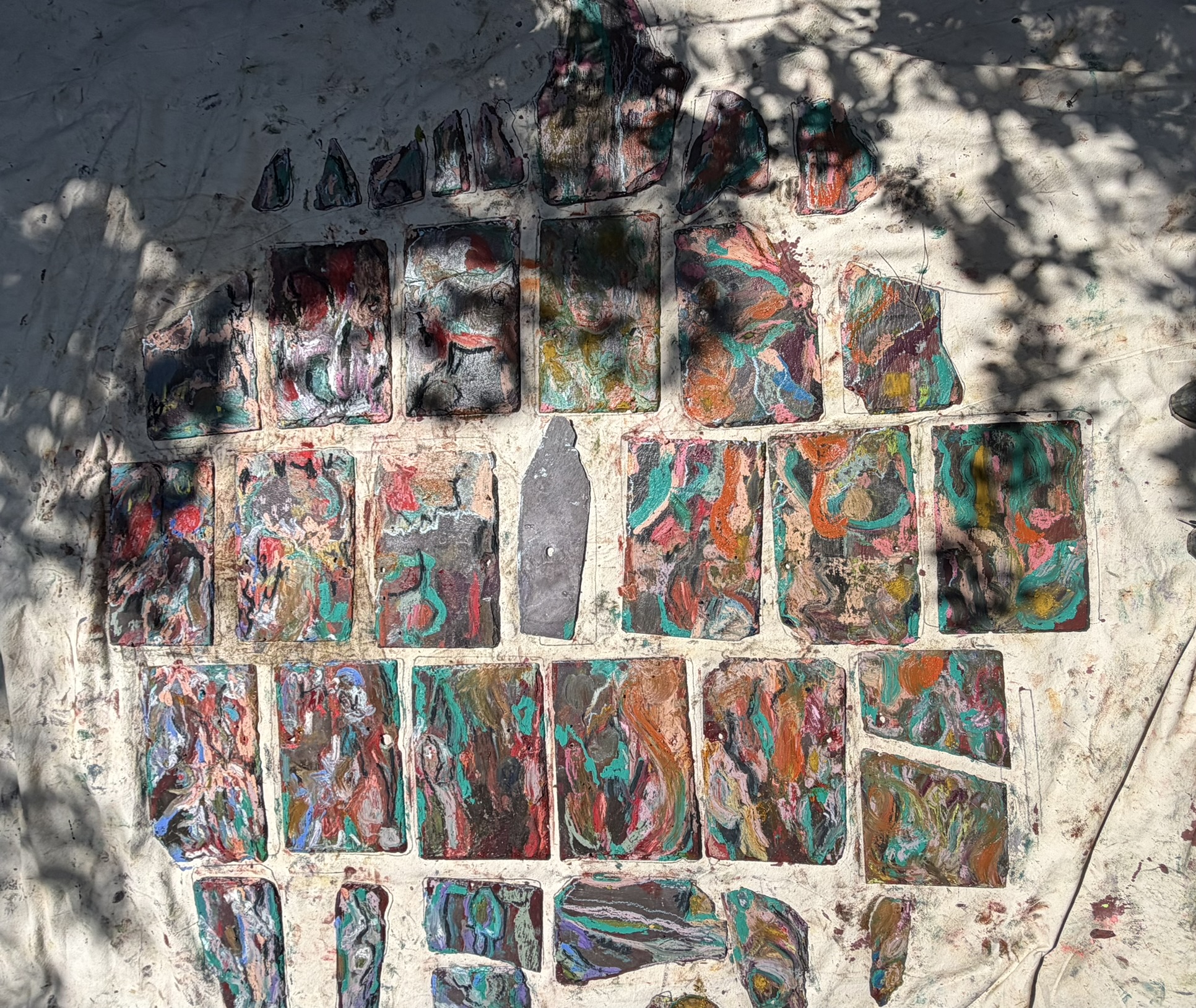 Painted slate works arranged outside while being prepared for painting and installation