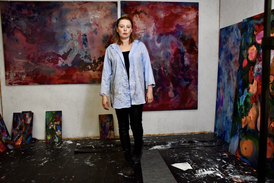 Rhiannon Rebecca Salisbury standing among her paintings in the studio